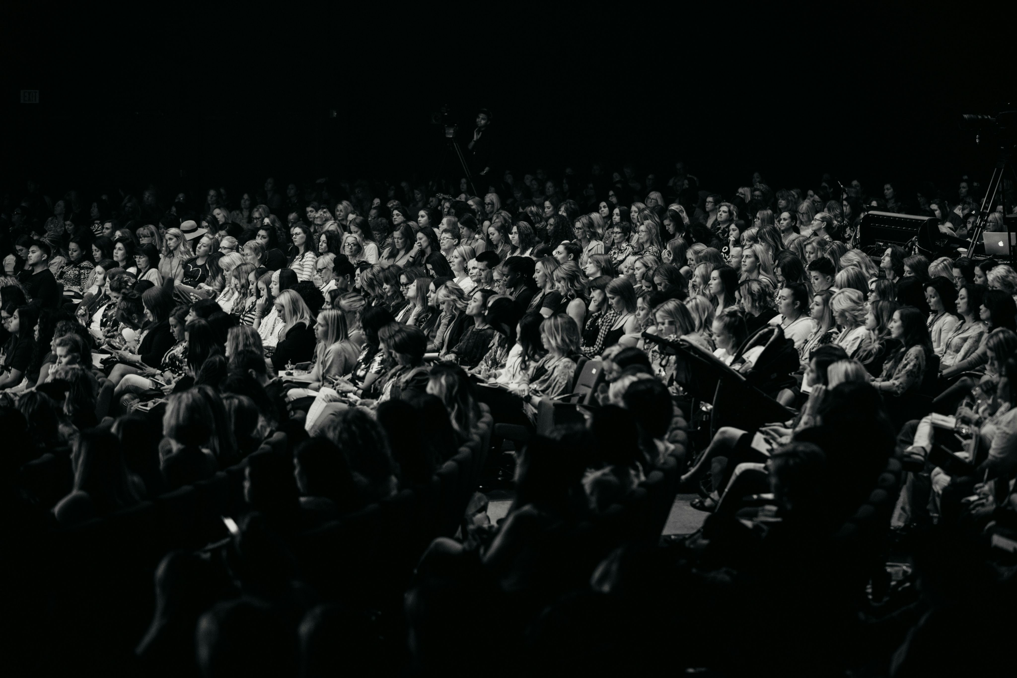 An audience watches a performance in a dark theater.