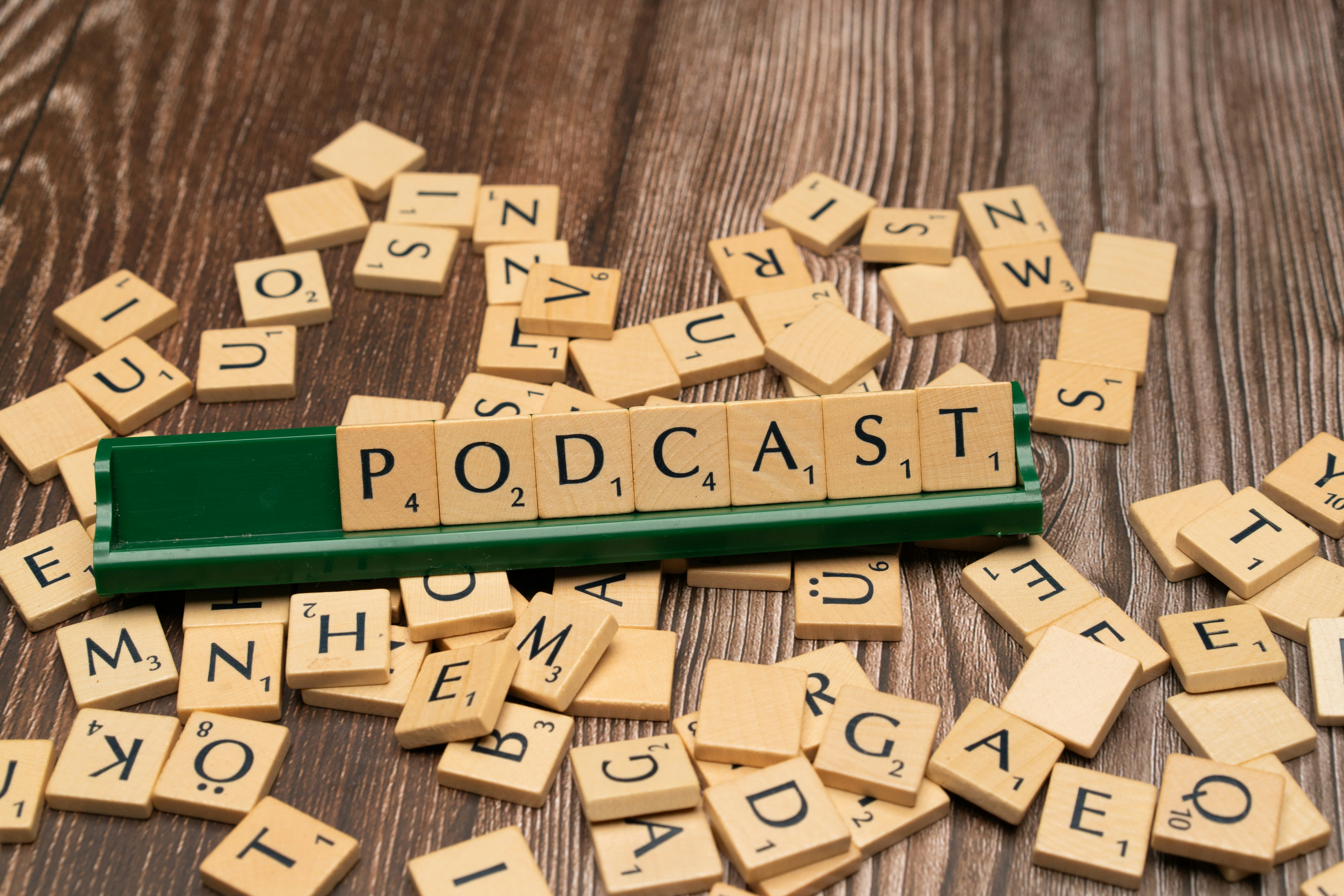 scrabbled letters spelling out the word podcast on a wooden table