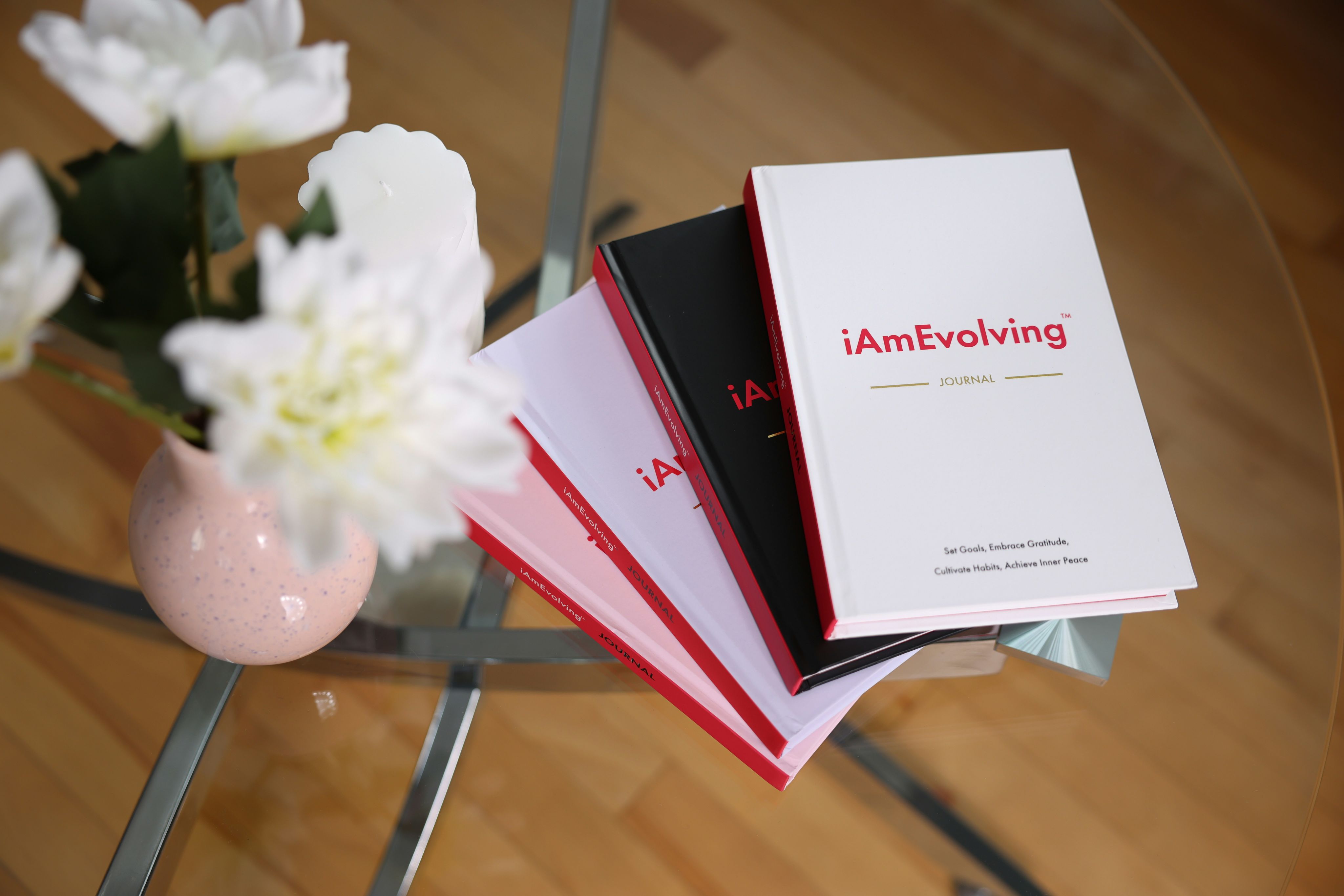 Books stacked on a glass table with flowers.